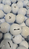 A close-up pile of white golf balls, including a central Bridgestone golf ball with a black 'B' logo and another with a black 'E6 SOFT' label.