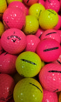 A close-up pile of golf balls in bright neon pink and fluorescent yellow-green, with visible Callaway and Supersoft branding on several balls.