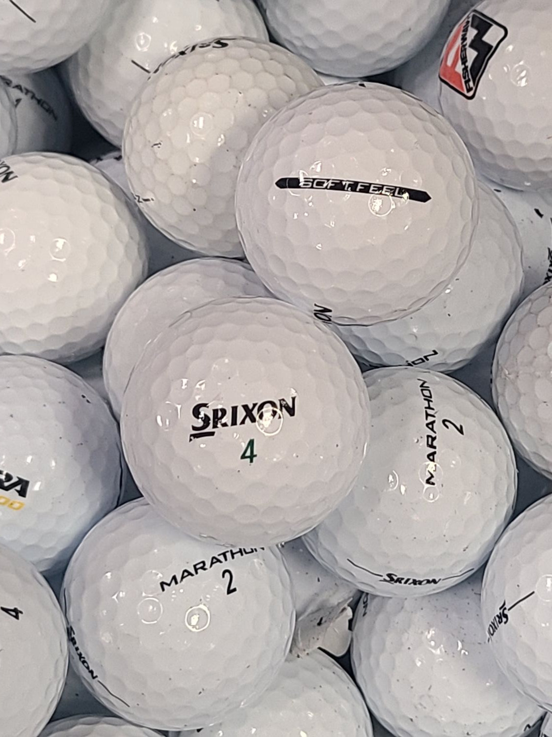 A close-up pile of white Srixon golf balls, with several balls visible showing the Srixon logo and model names like Marathon 2 and Marathon 4.