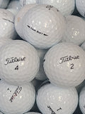 A close-up pile of white Titleist golf balls, some with black handwritten numbers and others showing the Titleist logo and TOUR SOFT text.